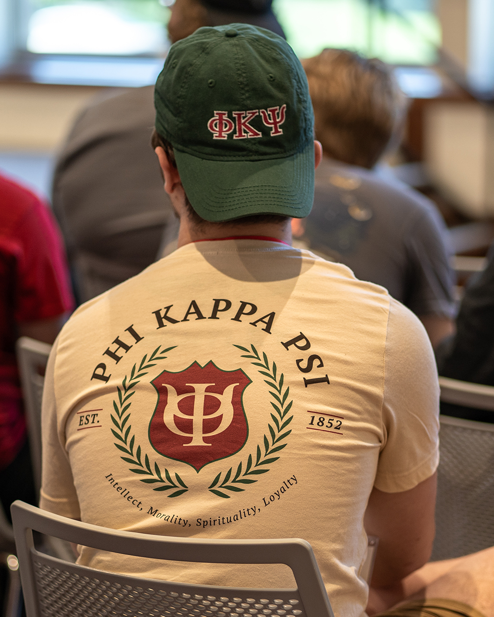 Image of undergraduate brother wearing Phi Psi t-shirt and hat while attending Campfire